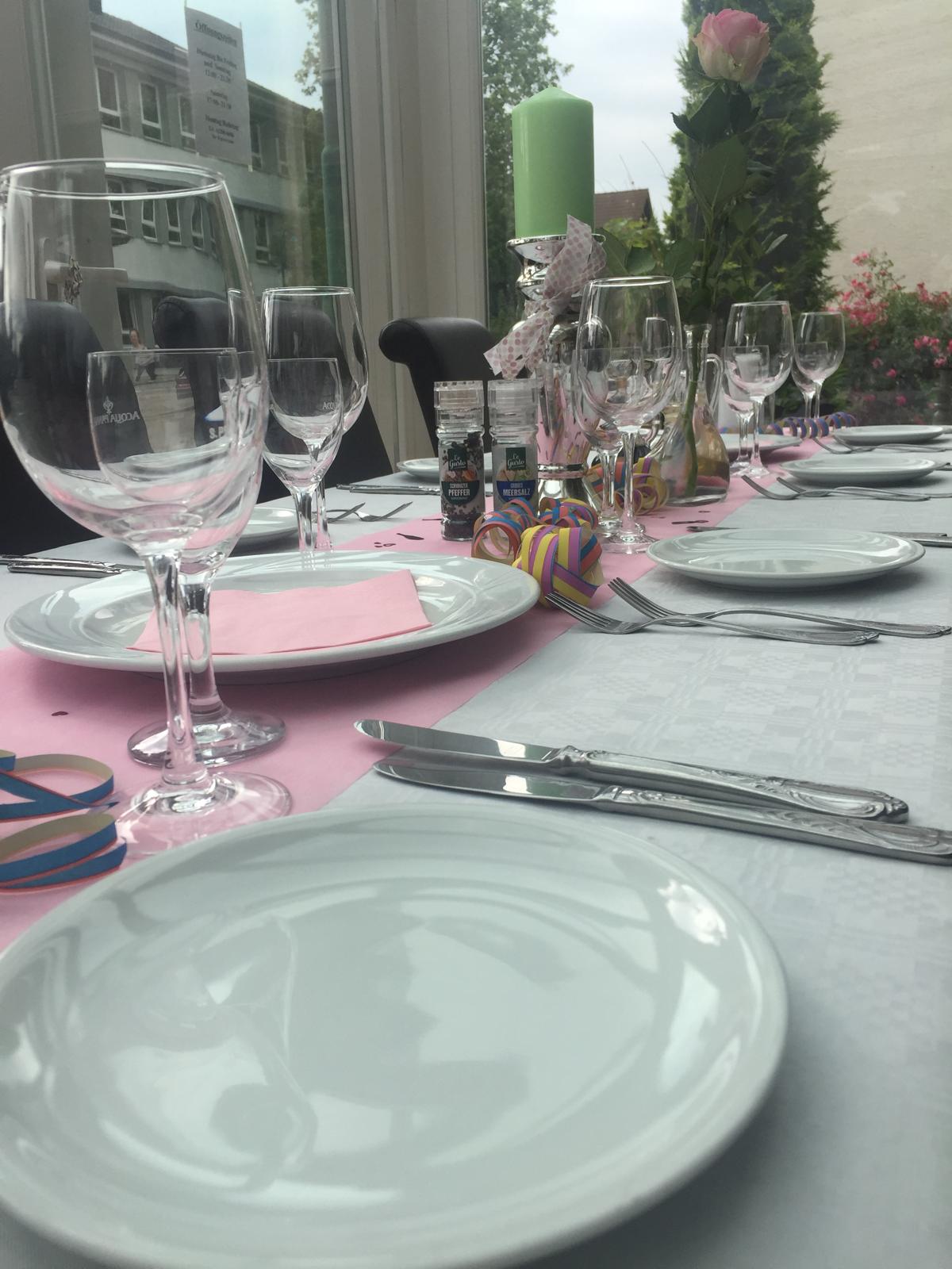 Liebevoll gedeckter Tisch mit Gläsern, Kerze und rosa Servietten