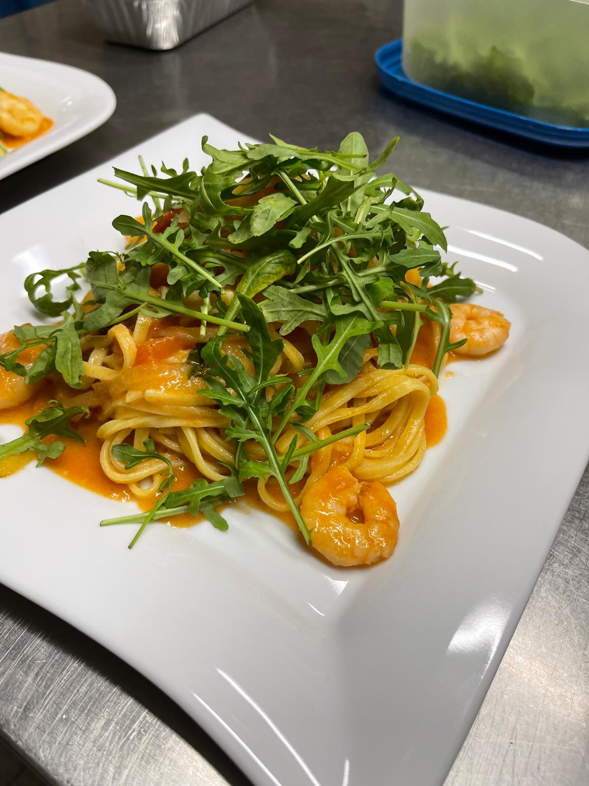 Spaghetti mit Gambas in Tomatensauce, gekrönt mit frischem Rucola