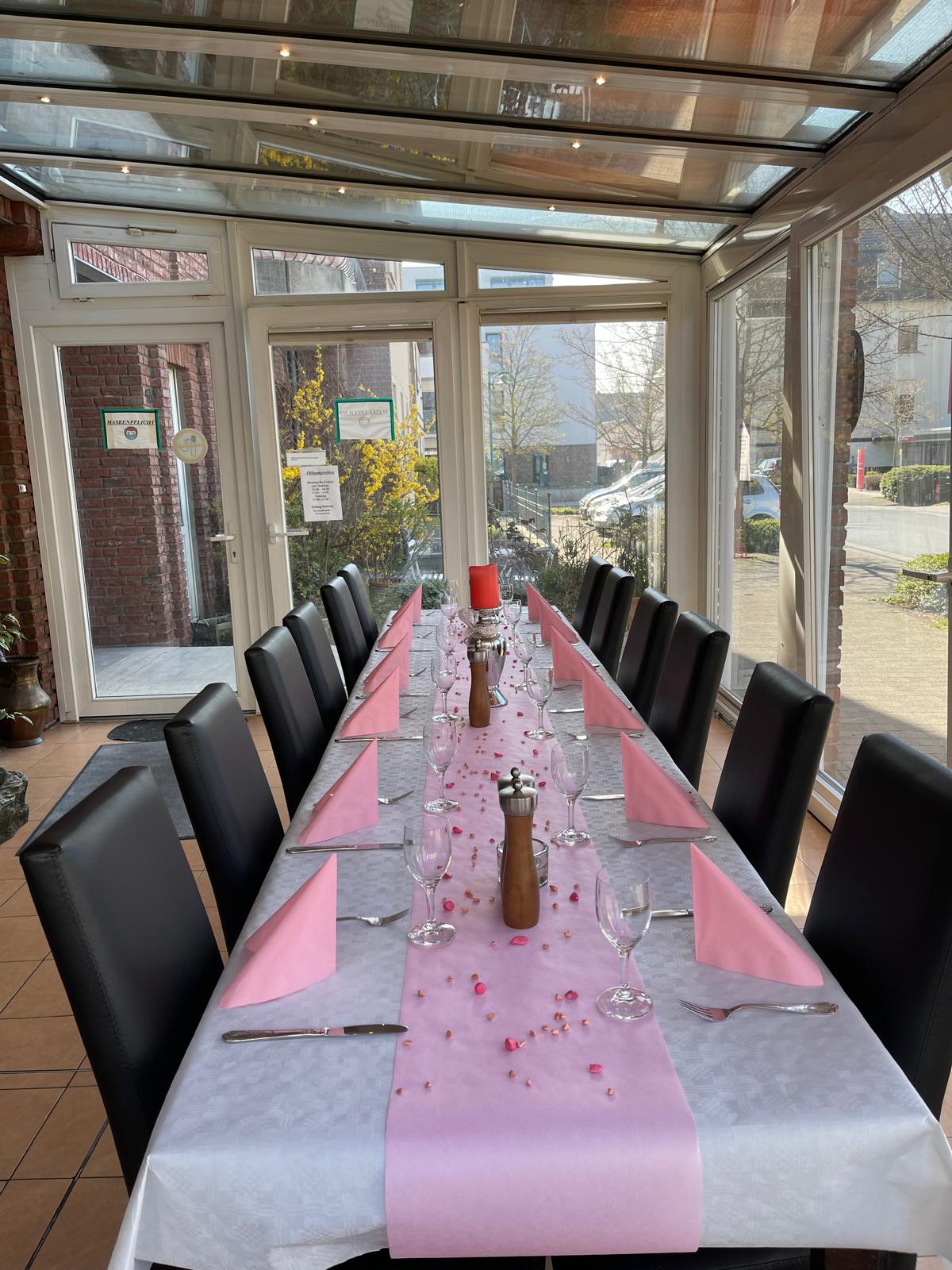Festlich gedeckte Tafel im lichtdurchfluteten Wintergarten des IL GUSTO